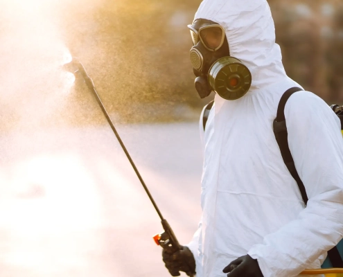 Personne en combinaison pulvérise désinfectant dehors